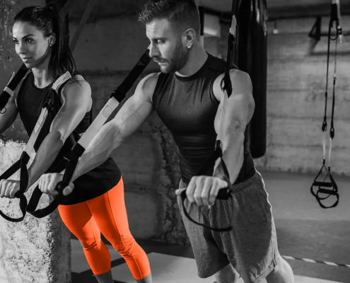 Junger Mann und junge Frau trainieren gemeinsam Functional Training mit Schlingentrainern zur Verbesserung von Kraft, Stabilität und Bewegungsqualität.