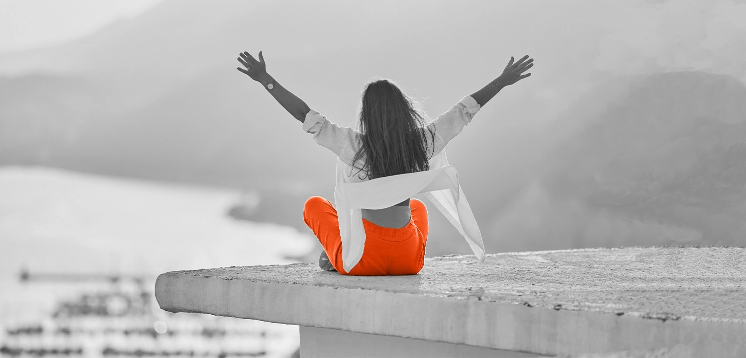 EliteMentor | System Mensch Person sitzt mit erhobenen Armen auf einer Mauer und symbolisiert Selbststeuerung, emotionale Stärke und die bewusste Steuerung des eigenen Zustands.